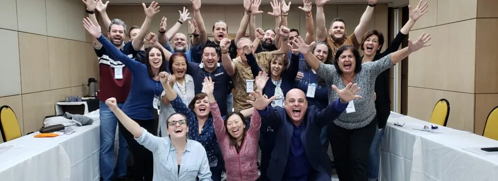 Turma de participantes de um workshop da Campos Consult com os braços erguidos ao final da sessão.
